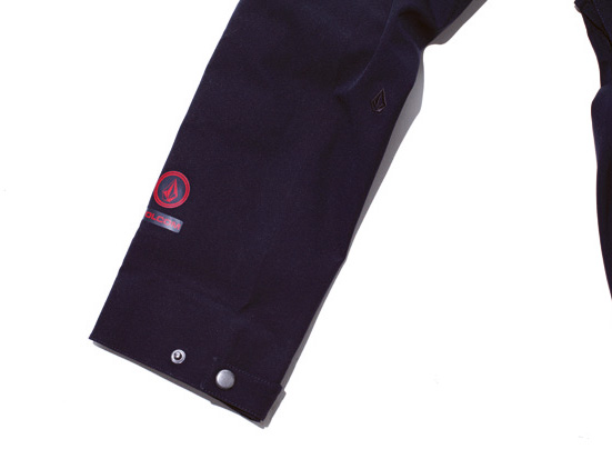 The hem of the arm is accented with a crimson logo and an embroidered black stone logo.